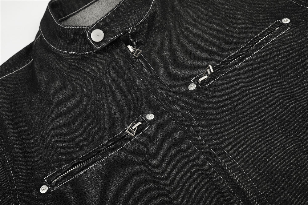 Close-up of black denim jacket front chest area with twin zip pockets and stand collar