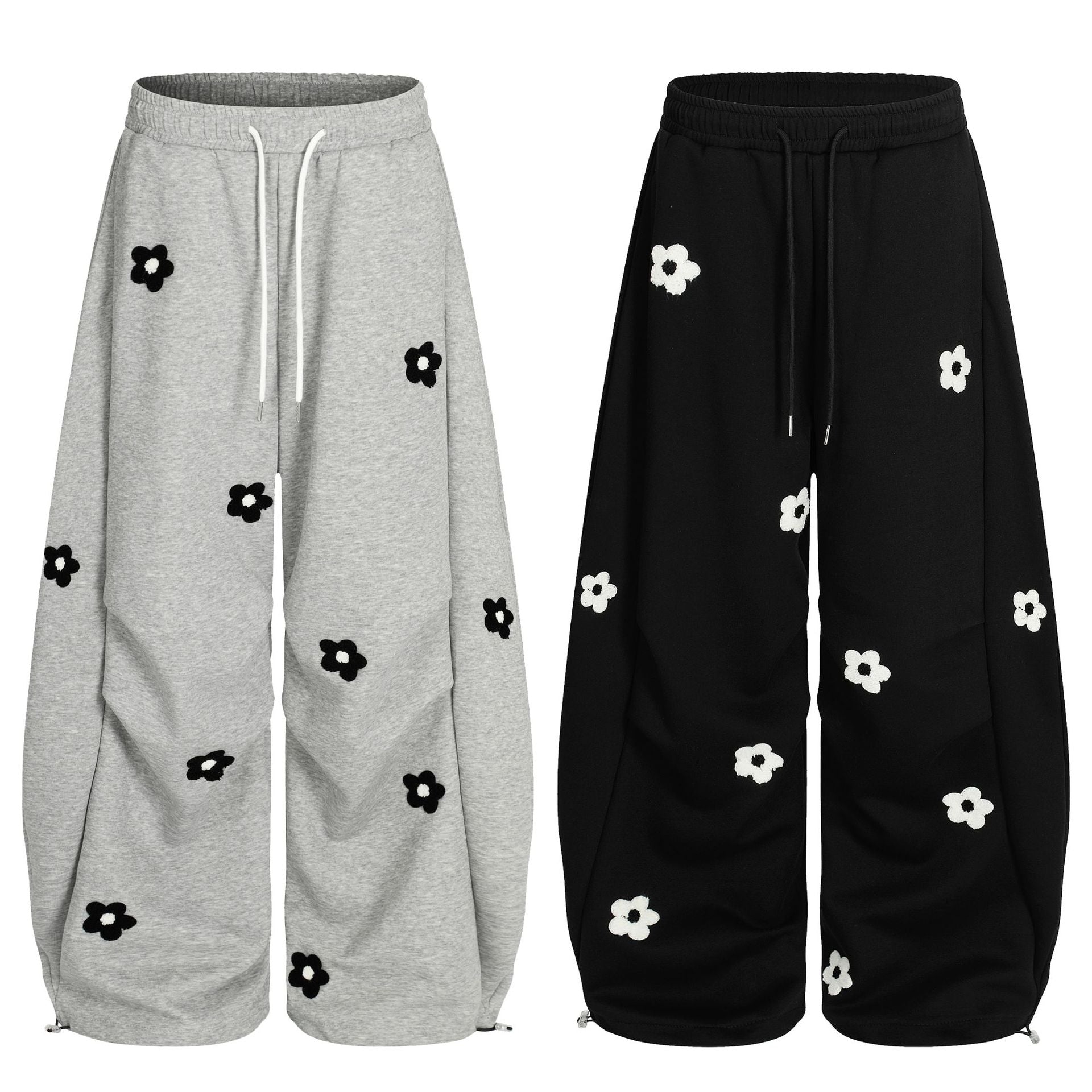 Pantalon de survêtement à jambes larges avec broderies intégrales de marguerites, gris chiné et noir, vue de face avec détail de bas zippé