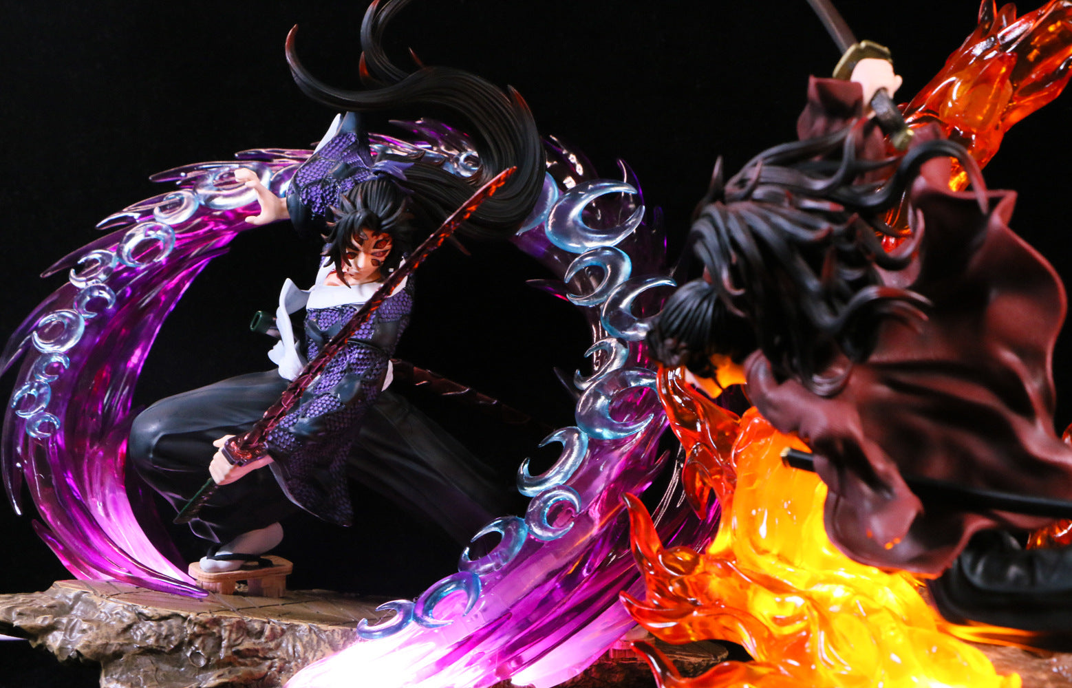 In an exciting anime collectible showdown, the Kokushibo Demon Slayer Figure - a 30cm PVC statue with glowing effects - wields a sword amidst purple swirls, facing off against another fiery figure engulfed in orange flames, capturing the vibrant energy and essence of battle.