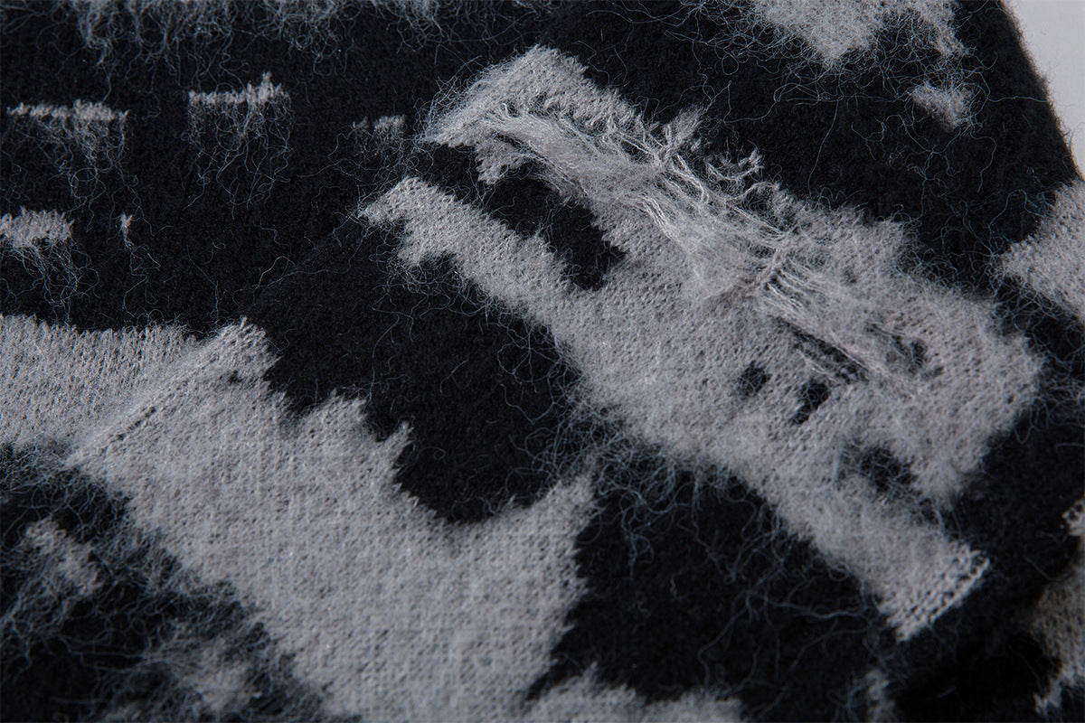 Close-up of a frayed section in the black and gray distressed jacquard knit sweater fabric