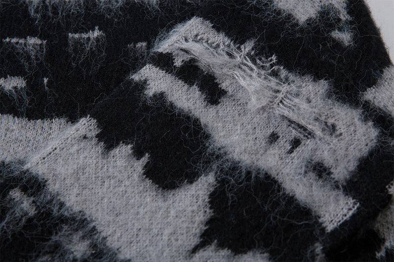 Close-up of a frayed section in the black and gray distressed jacquard knit sweater fabric