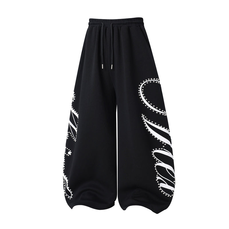 Pantalon de survêtement à jambes larges avec imprimé graffiti cursif orné de rivets