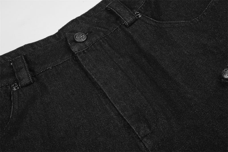 Close-up of black denim waistband, pleat seam, and front button detail