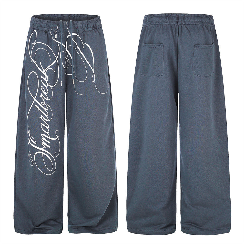 Pantalon de survêtement bleu ardoise à jambes larges, avec grande inscription cursive imprimée sur le devant de la jambe, taille élastique à cordon, vue de face et de dos