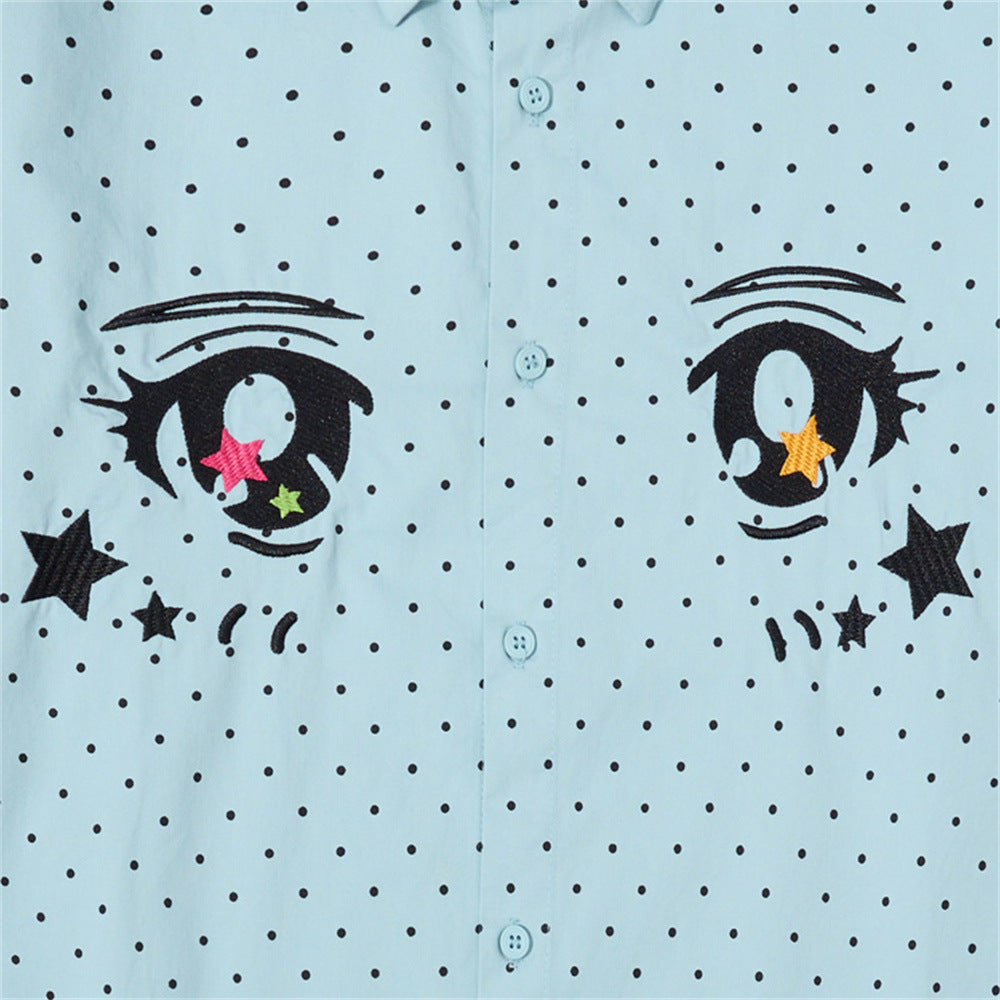 Close-up of the light blue shirt front showing embroidered anime eyes and polka dots