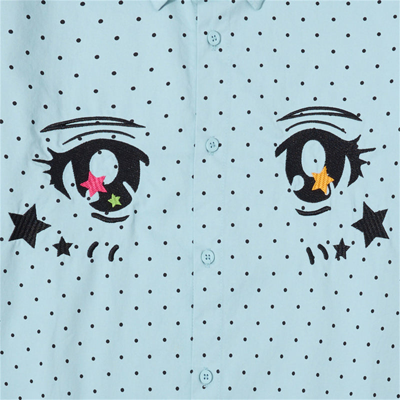 Close-up of the light blue shirt front showing embroidered anime eyes and polka dots