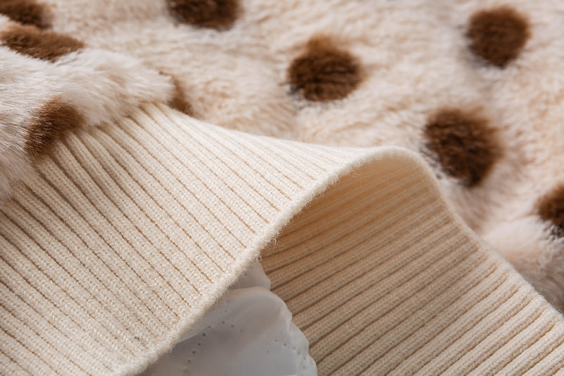 Close-up of the cream ribbed hem and fluffy polka dot faux shearling jacket fabric