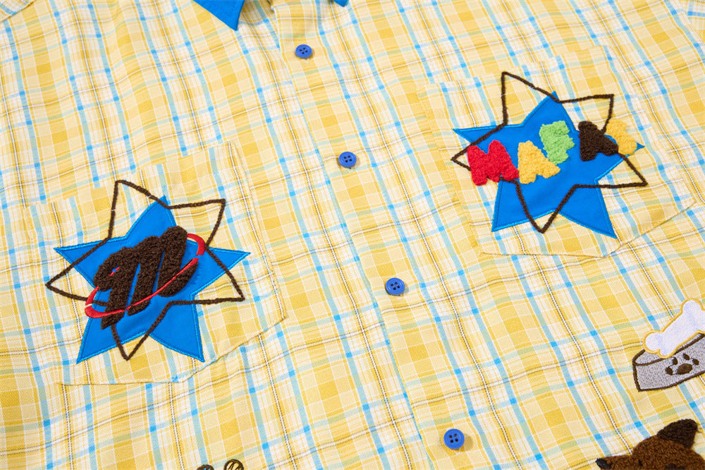 Upper front of yellow plaid shirt showing blue buttons and star embroidery
