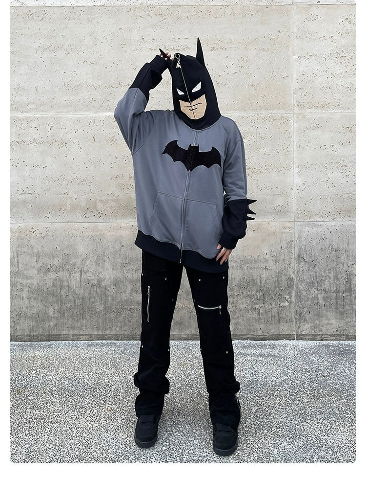 A person models the Seakoff Batman-Inspired Hoodie—a 400GSM oversized grey and black zip-up sweatshirt—against a concrete backdrop, hand on head, capturing true superhero streetwear vibes.