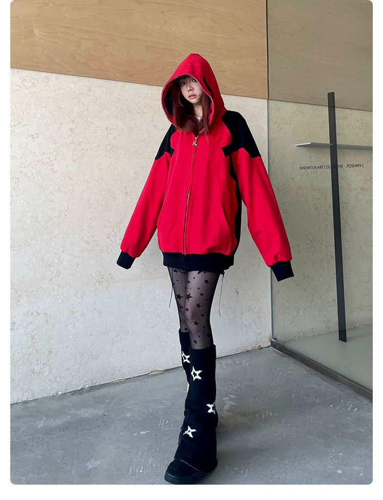 A person in a Seakoff Deadpool-Inspired Hoodie, black star-patterned tights, and star-adorned boots stands against a beige and black wall. The hood is up with their hands tucked in the pockets of the 400GSM oversized red and black zip-up superhero sweatshirt.