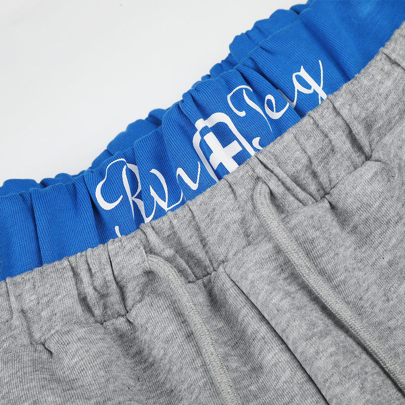 Close-up of blue waistband with white script over gray fleece sweatpants