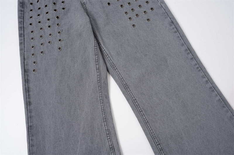 Lower leg view of washed grey jeans with metal eyelet rows near the thigh
