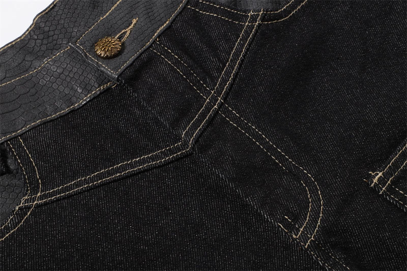 Close-up of black jeans waistband with textured belt panel, button, and tan stitching