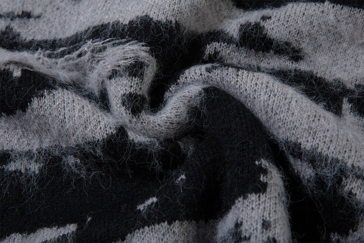 Close-up of folded black and gray distressed jacquard knit fabric showing fuzzy fibers and texture
