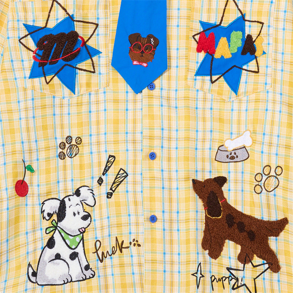 Front of yellow plaid shirt with blue tie, cartoon dog embroidery, and star patches