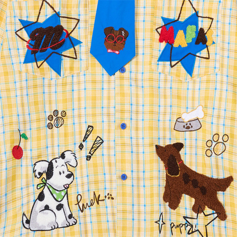 Front of yellow plaid shirt with blue tie, cartoon dog embroidery, and star patches