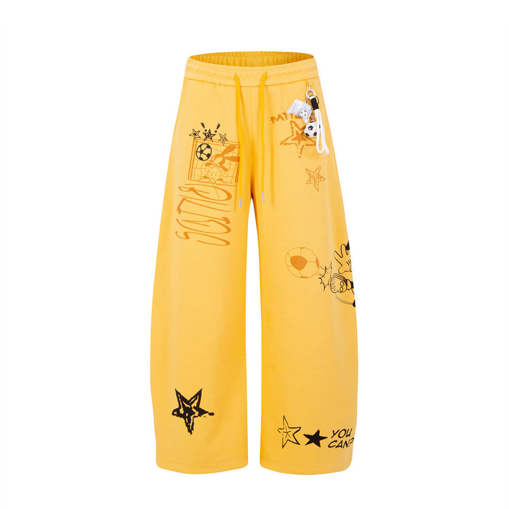 Yellow wide-leg sweatpants with Mickey Mouse and cartoon graffiti graphic print, detachable football keychain charm, front an