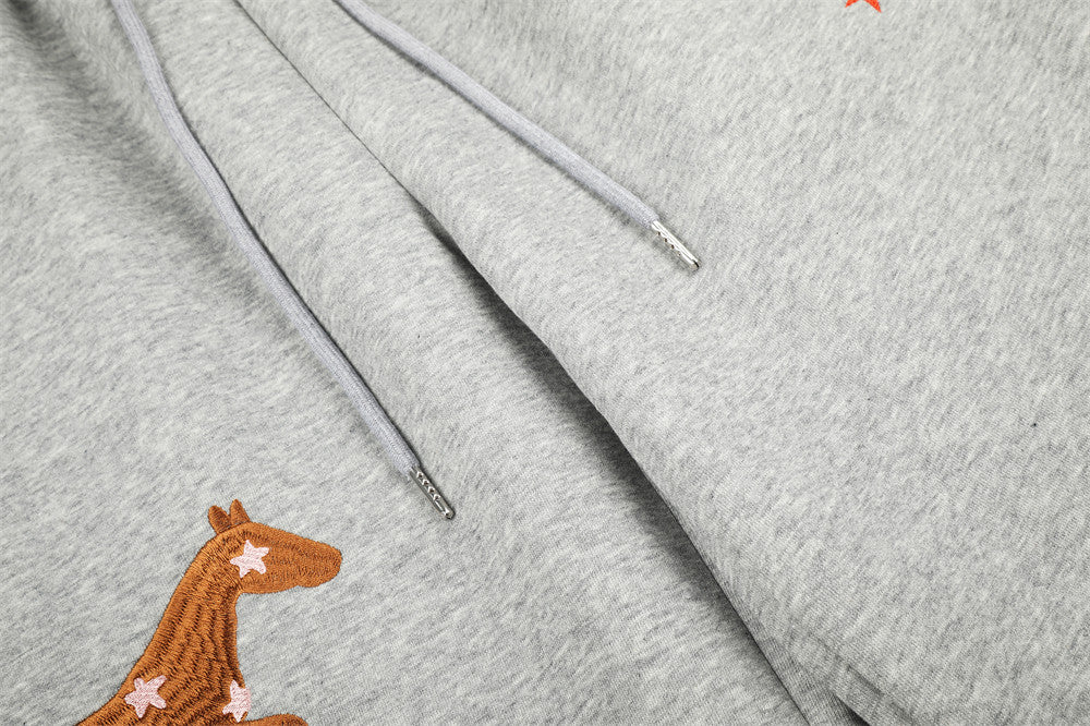 Close-up of gray sweatpants drawstrings and horse embroidery detail