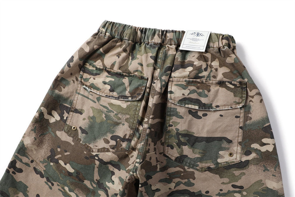 Back view of camouflage cargo shorts with flap pockets and label at waistband