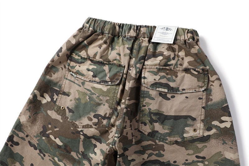 Back view of camouflage cargo shorts with flap pockets and label at waistband