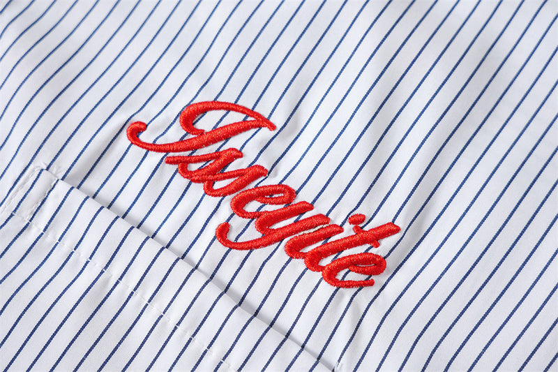 Close-up of red embroidered script on blue and white striped fabric