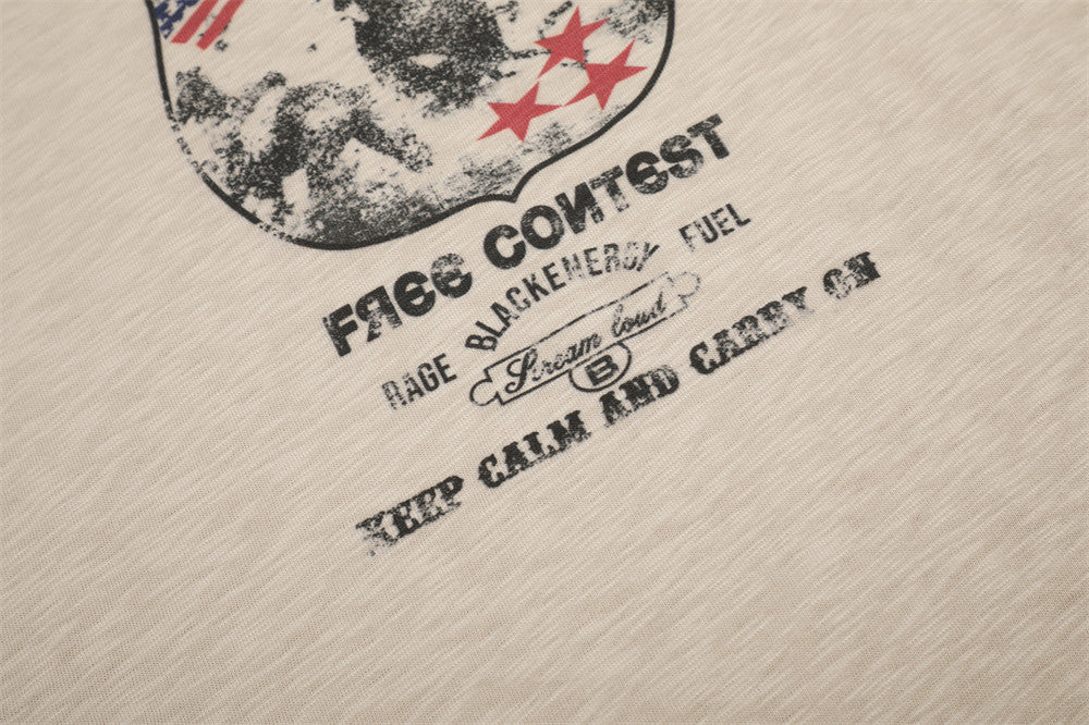 Close-up of printed text beneath the front badge graphic on beige tee