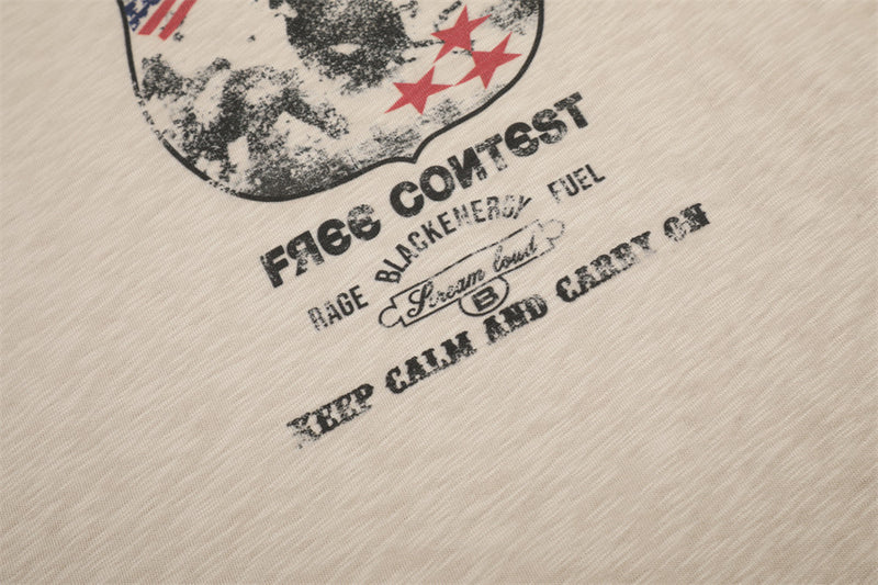 Close-up of printed text beneath the front badge graphic on beige tee