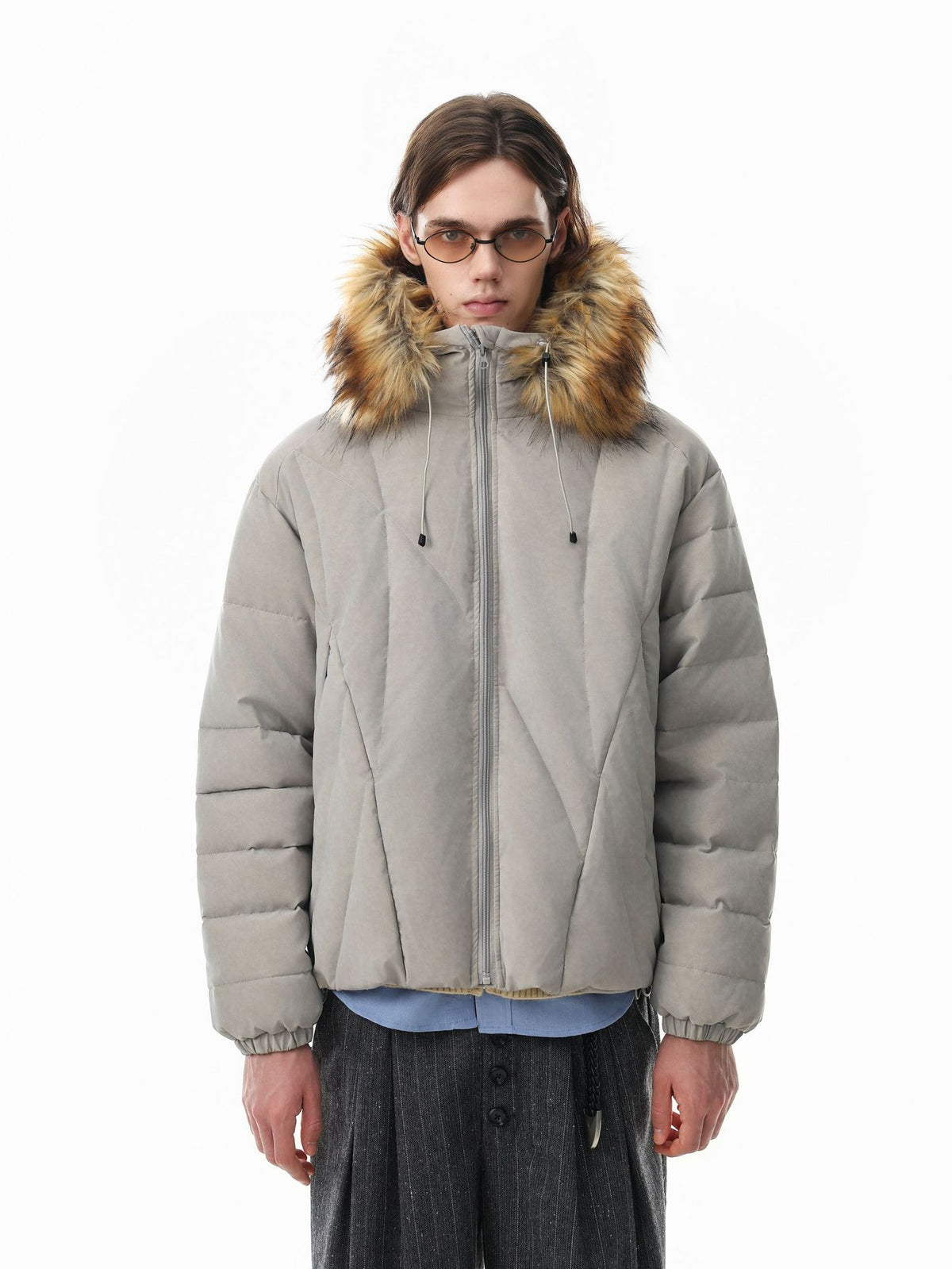 Oversized diamond-quilted puffer jacket with faux fur trim hood in grey, worn by male model with wide-leg trousers