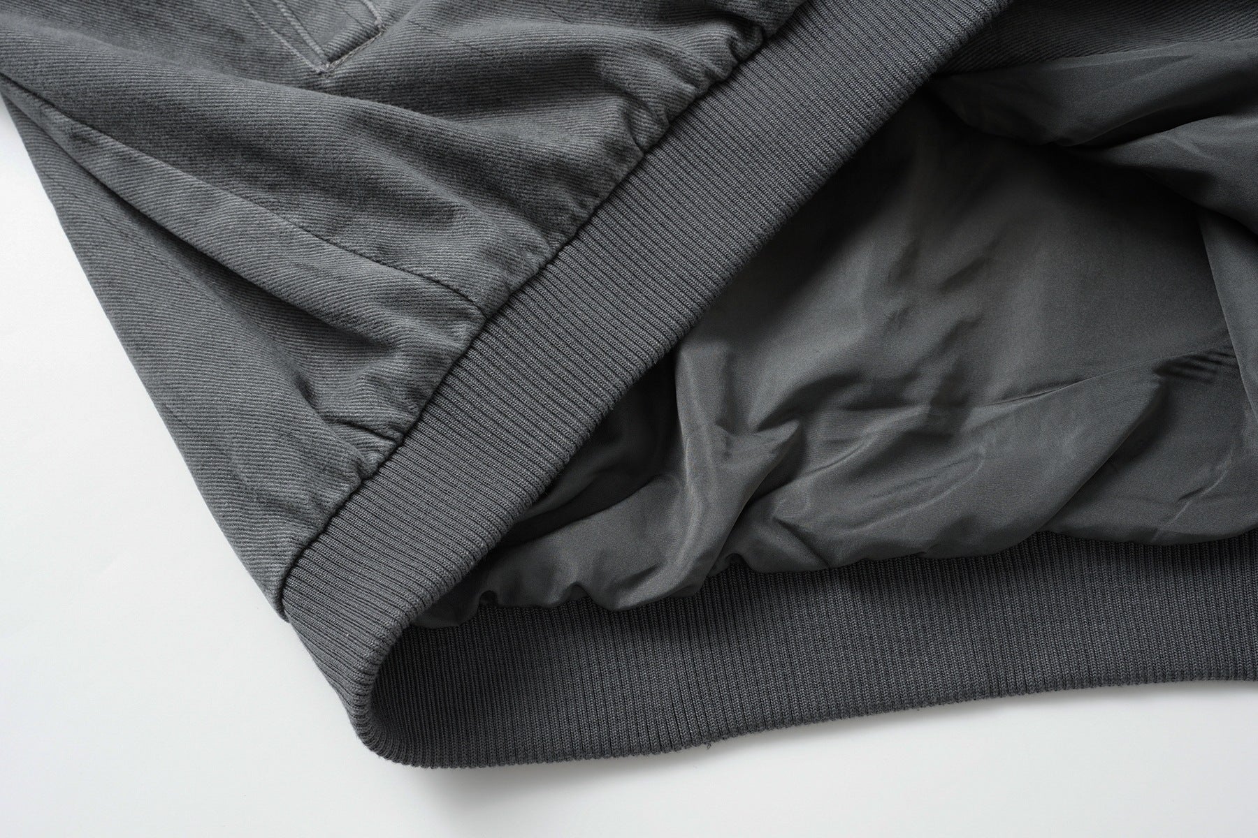 Veste bomber en jean délavé déconstruite à empiècement croisé et coutures effilochées