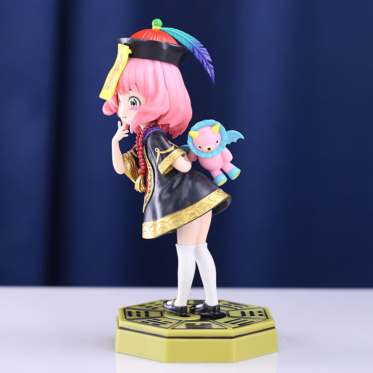 This captivating 18 cm Spy x Family PVC figure features Anya Forger with pink hair, a black and gold outfit, white stockings, and a feathered hat. She poses with a finger to her lips and a small winged creature on her back, set on an ornate base.