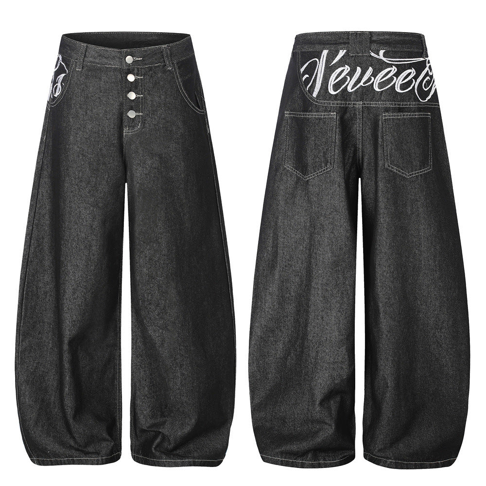 Men's dark black wide-leg balloon jeans with white script embroidery on back waistband and exposed button fly