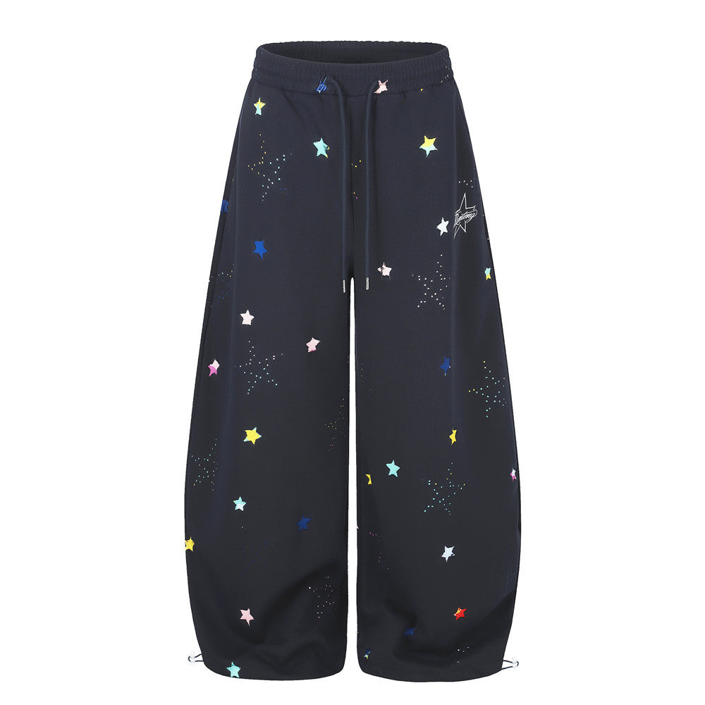 Wide-leg sweatpants with multicolor star print and curved hem in navy blue, front view