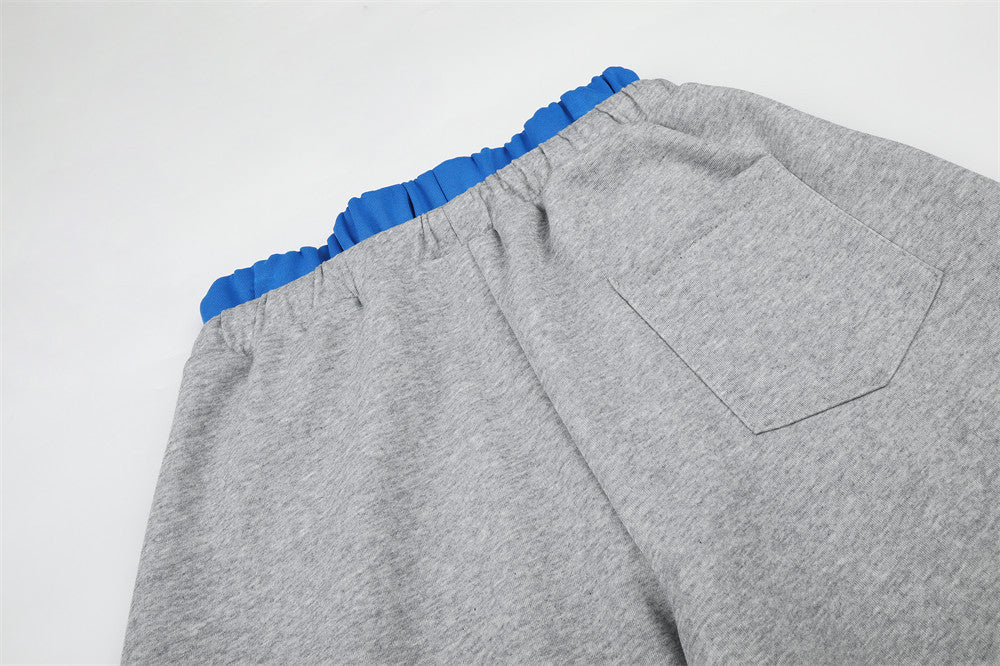 Close-up of gray sweatpants back pocket and blue waistband edge