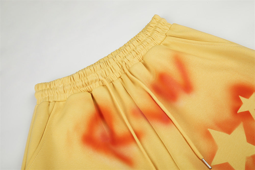 Close-up of yellow sweatpants waistband and drawstring with orange spray-dye and star print