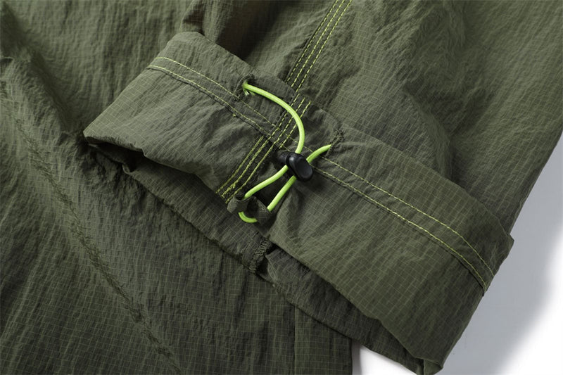 Close-up of an olive pants hem with a bright green drawcord and black cord lock