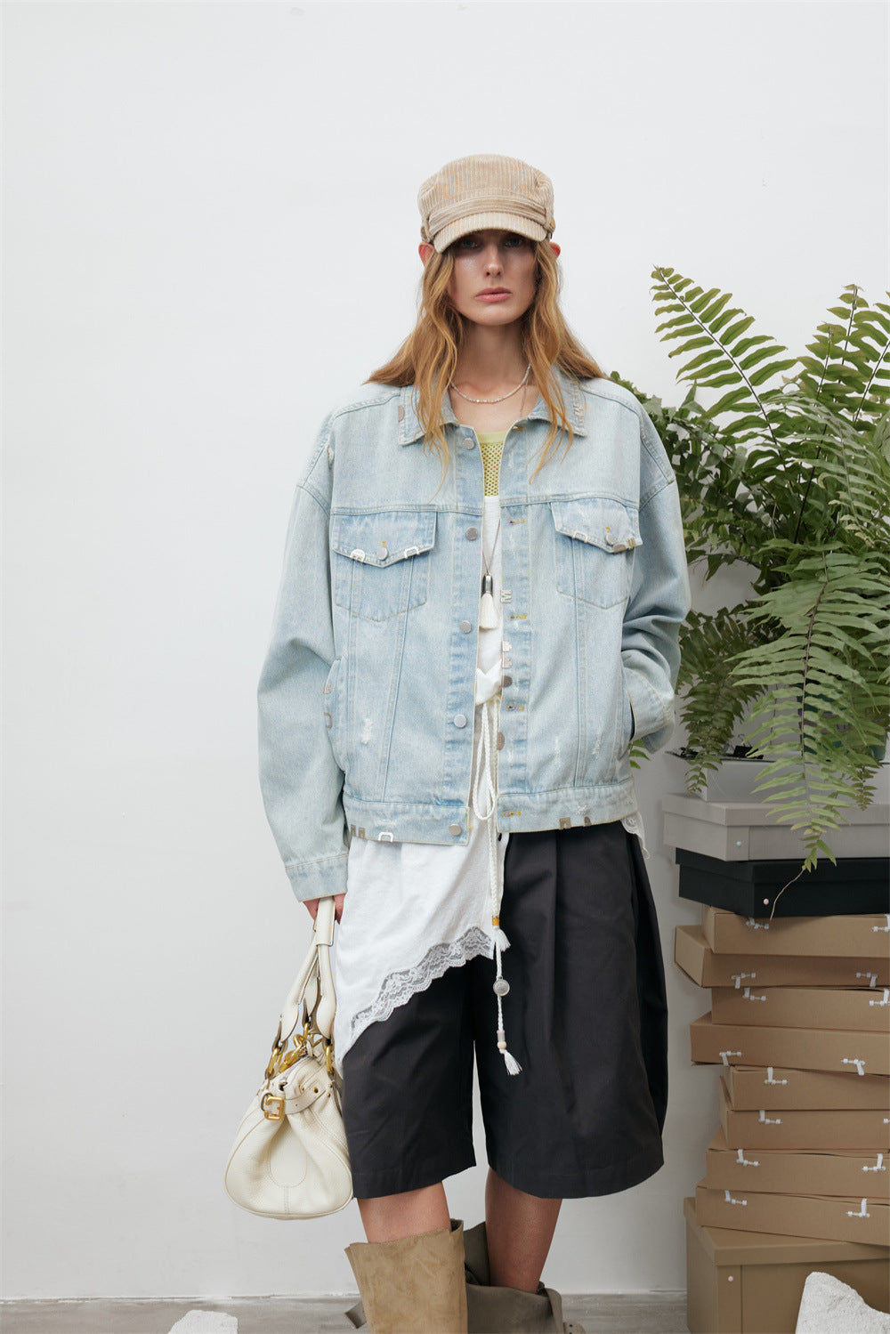 Front model view of a light wash denim jacket with flap pockets, silver-tone buttons, and frayed details