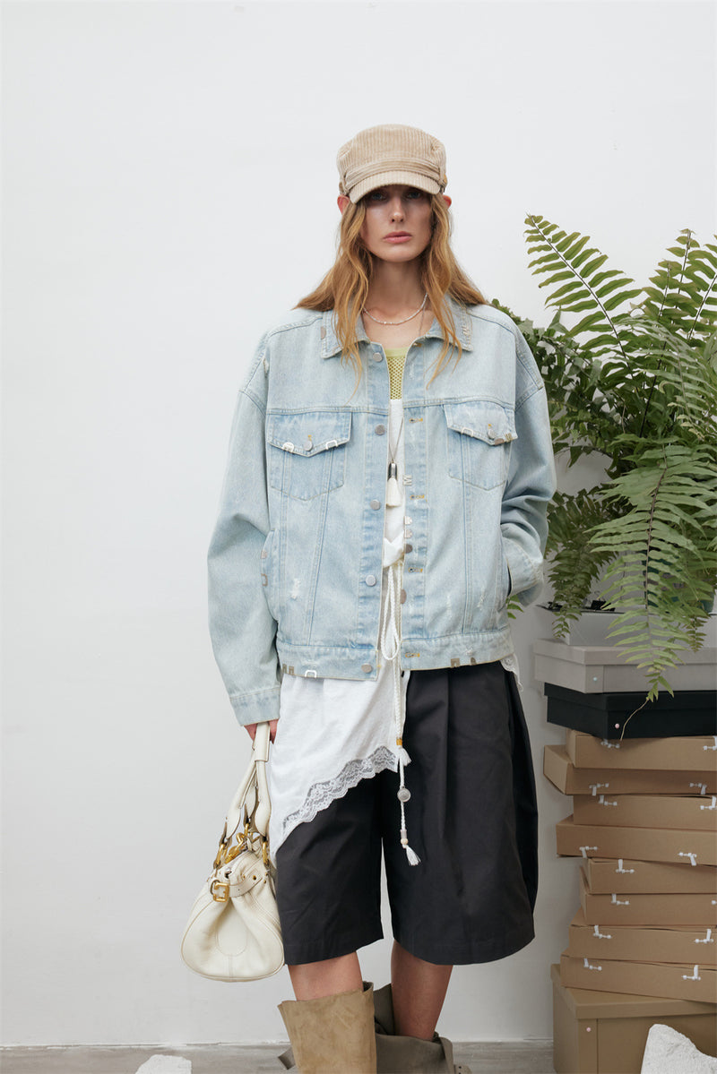Front model view of a light wash denim jacket with flap pockets, silver-tone buttons, and frayed details