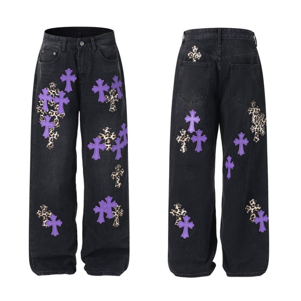 Men's baggy wide-leg jeans with oversized cross appliqué patches on washed black denim, front and back view