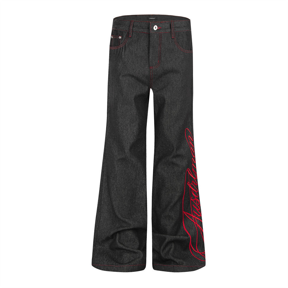 Herrenjeans mit Schlag aus schwarzem Raw Denim, roter kursiver Schriftstickerei am unteren Bein und roten Kontrastnähten