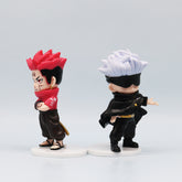 The Jujutsu Kaisen Q Edition Spell Return set includes two figures on white bases: one with red spiky hair, a red scarf, and shirt with crossed arms; the other with white spiky hair, a black blindfold, and an extended arm. Perfect for any PVC collectible set!.