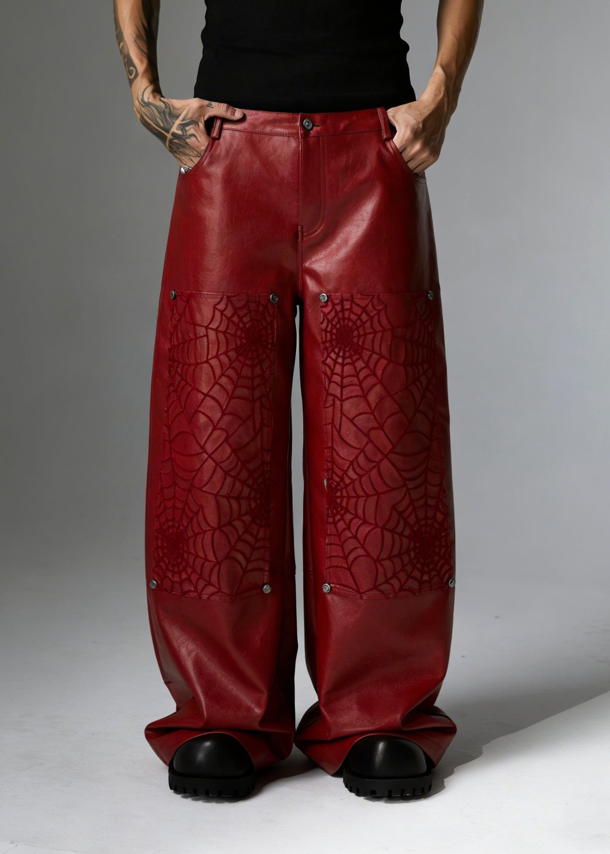 Wide-leg faux leather pants with spiderweb embossed panels and silver rivets in red and black colorways