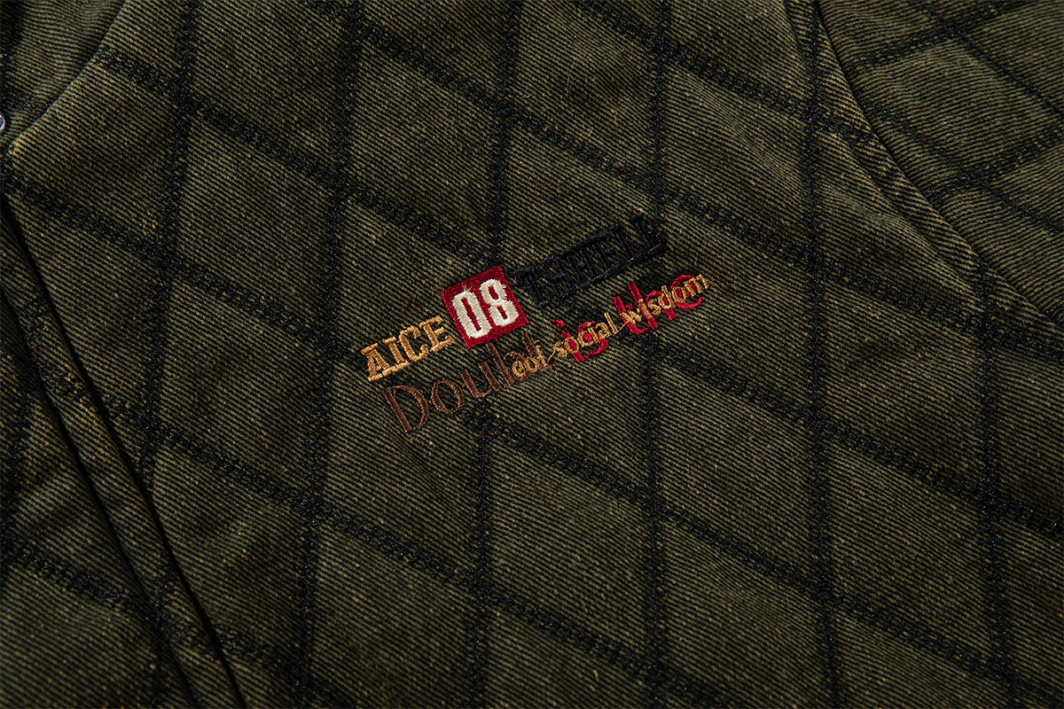 Close-up of embroidered chest branding on olive green diamond-quilted jacket fabric