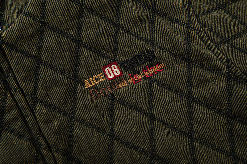 Close-up of embroidered chest branding on olive green diamond-quilted jacket fabric