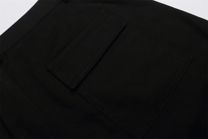 Close-up of black shorts back pocket with flap and top-stitched edges