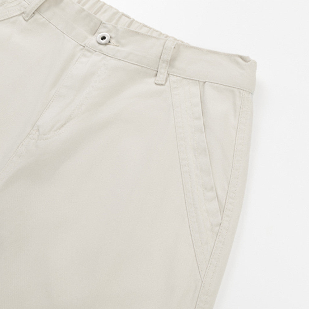 Close-up of cream pants front pocket and side seam