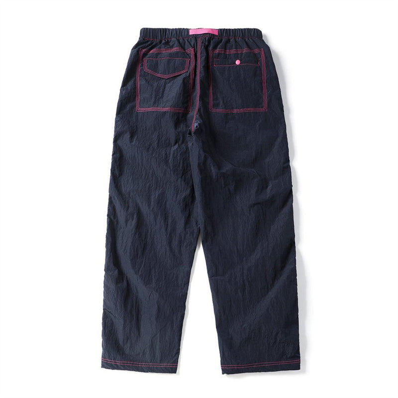 Back view of navy parachute pants featuring two outlined rear pockets with pink stitching