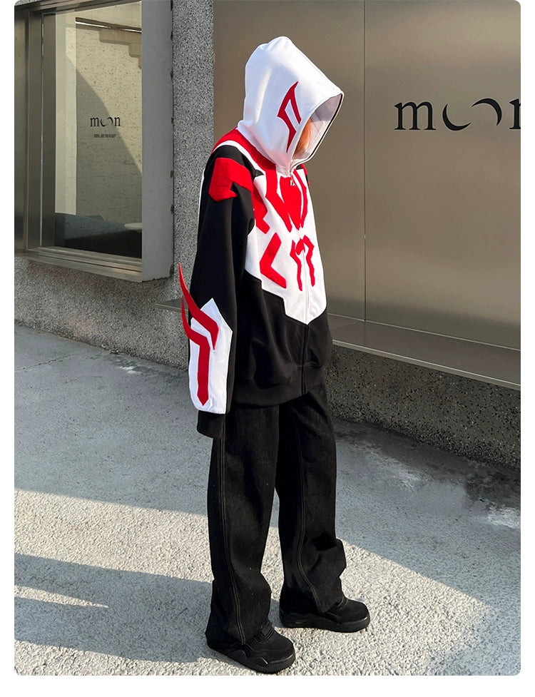 A person wears a Seakoff Superhero-Inspired Hoodie, a 400GSM oversized black, red, and white zip-up sweatshirt. They pair it with sleek black pants and shoes, standing on a sidewalk facing reflective windows with a sign reading &quot;moon,&quot; showcasing streetwear fashion at its finest.