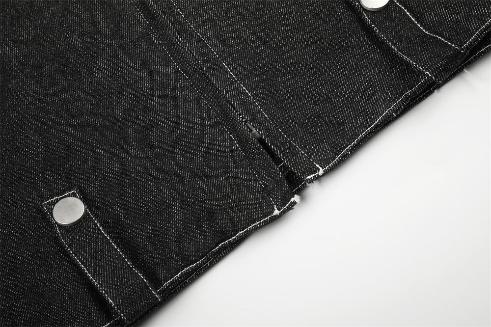 Close-up of black denim jacket hem with snap tab and center seam stitching