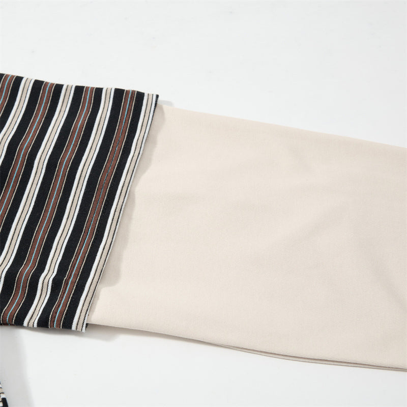 Close-up of cream long sleeve cuff layered under striped short sleeve