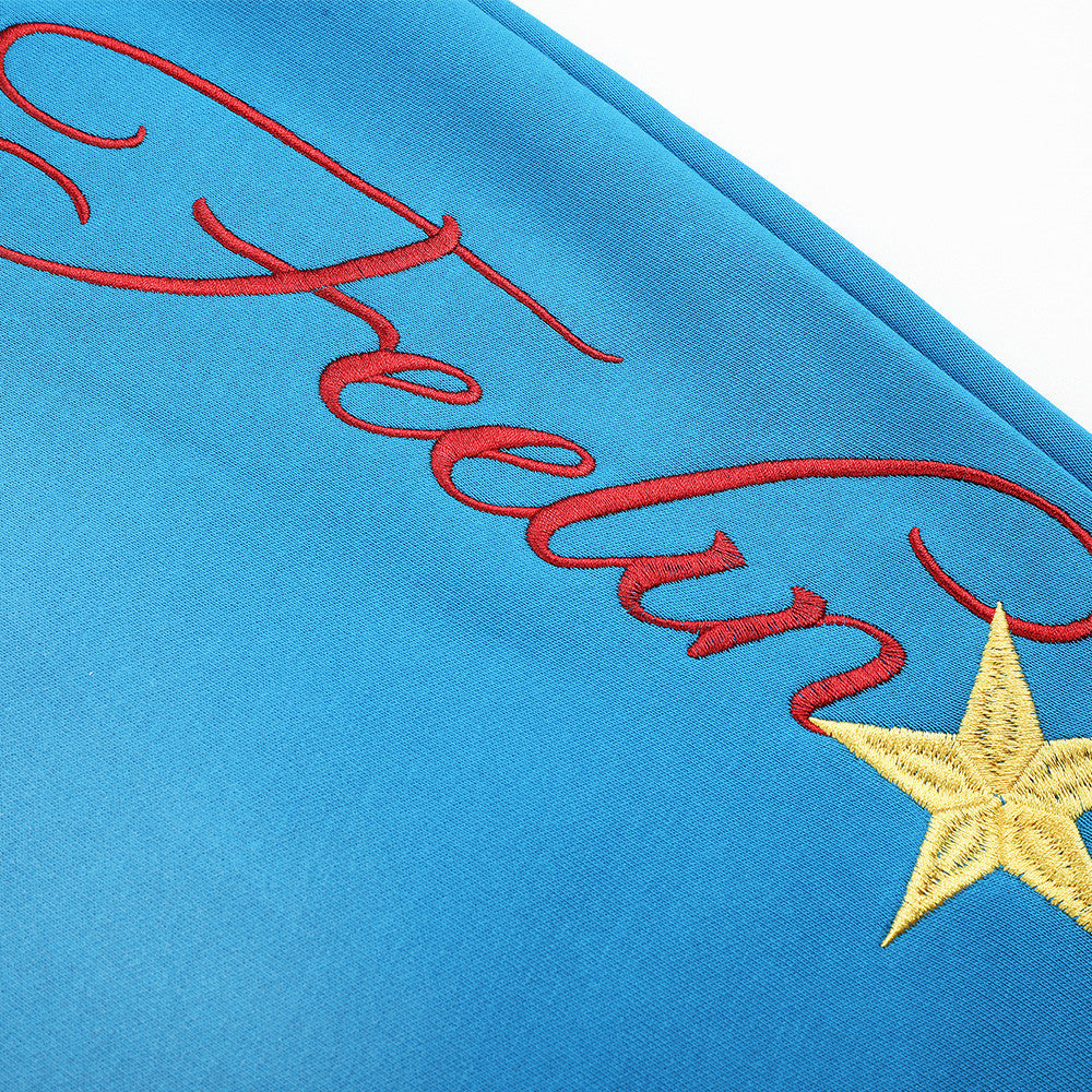 Close-up of script embroidery and yellow star on blue sweatpants